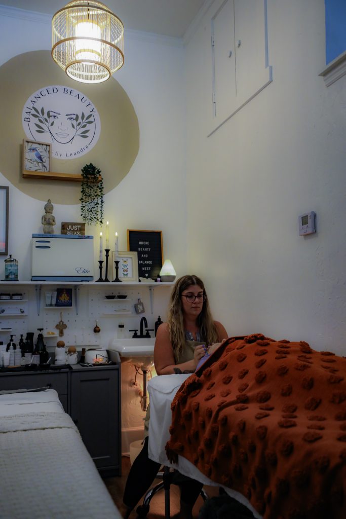 a woman sitting on a bed in a room with a red blanket