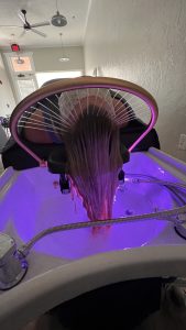 Close-up of guest using hydrotherapy basin with glowing LED light therapy in Fort Pierce