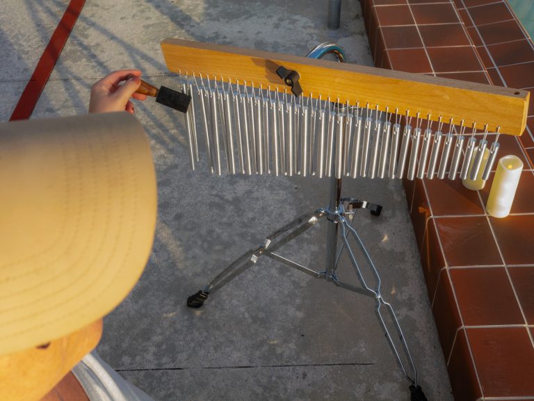 Person playing metal chimes outdoors.